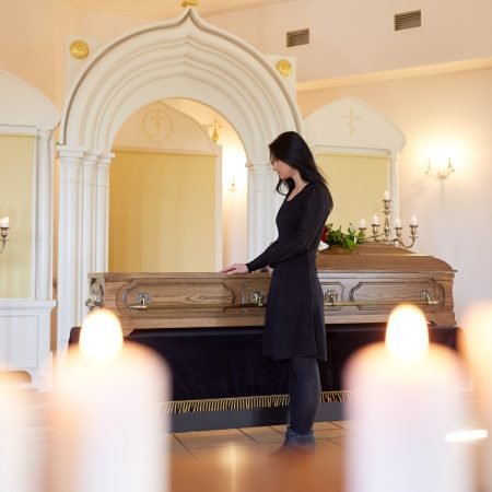 burial, people and mourning concept - sad woman with coffin at funeral in orthodox church